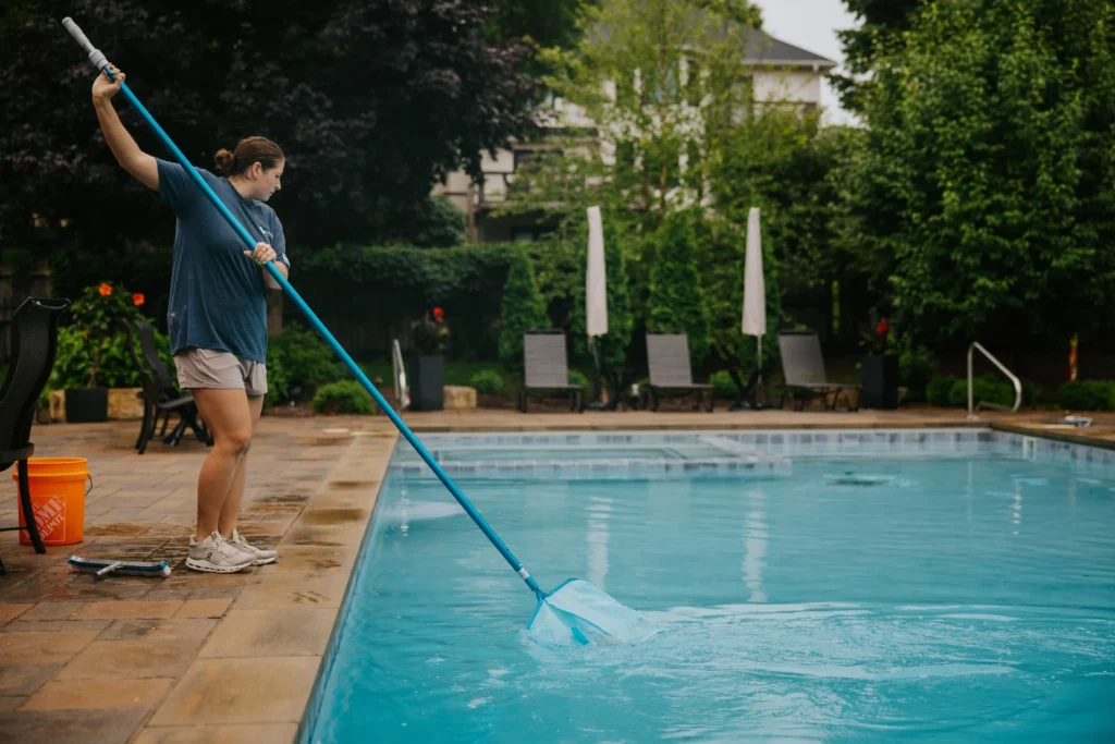 a Parklane Pool Co. employee uses a net to clean debris from a backyard residential pool